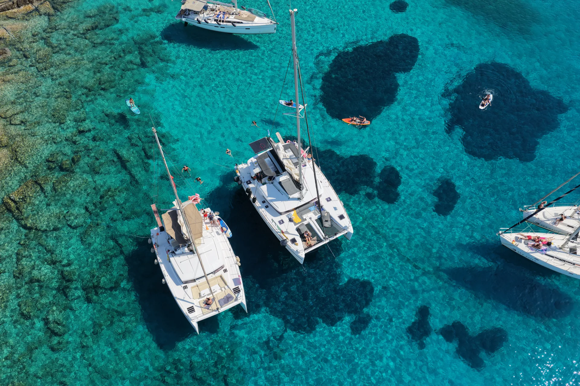 Aerial view of catamarans above clear Greek waters