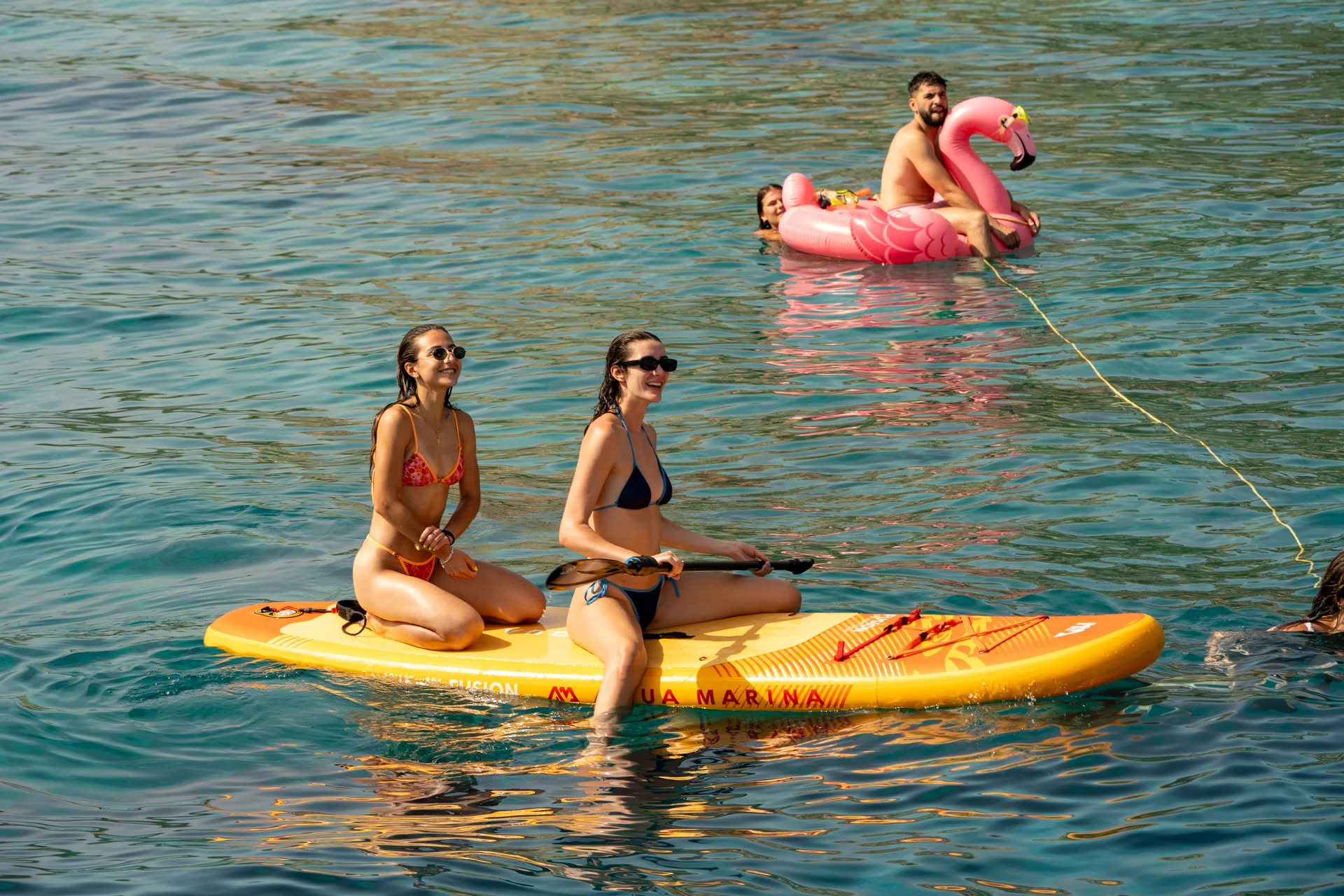 Guests relaxing on paddleboards and a float during a cruise