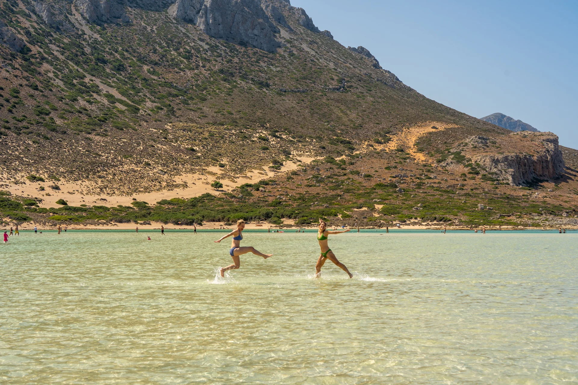 Guests wading through a shallow lagoon beside the mountains