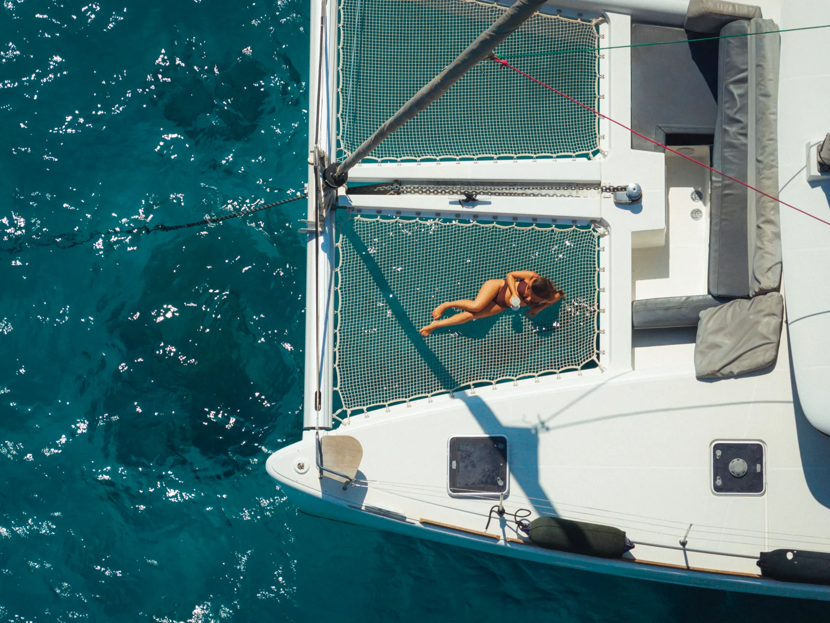 Aerial view of a guest relaxing on a catamaran bow