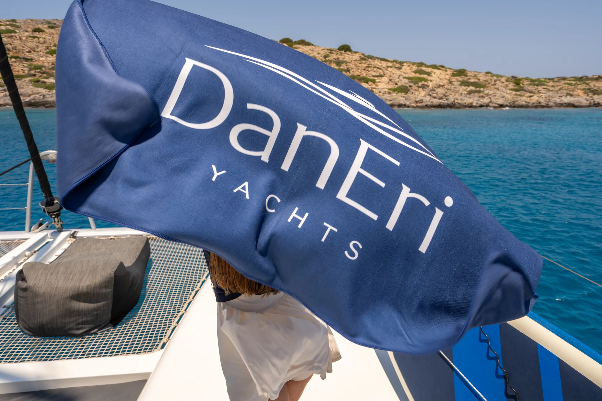 DanEri Yachts flag on the catamaran deck beside the rocky coast