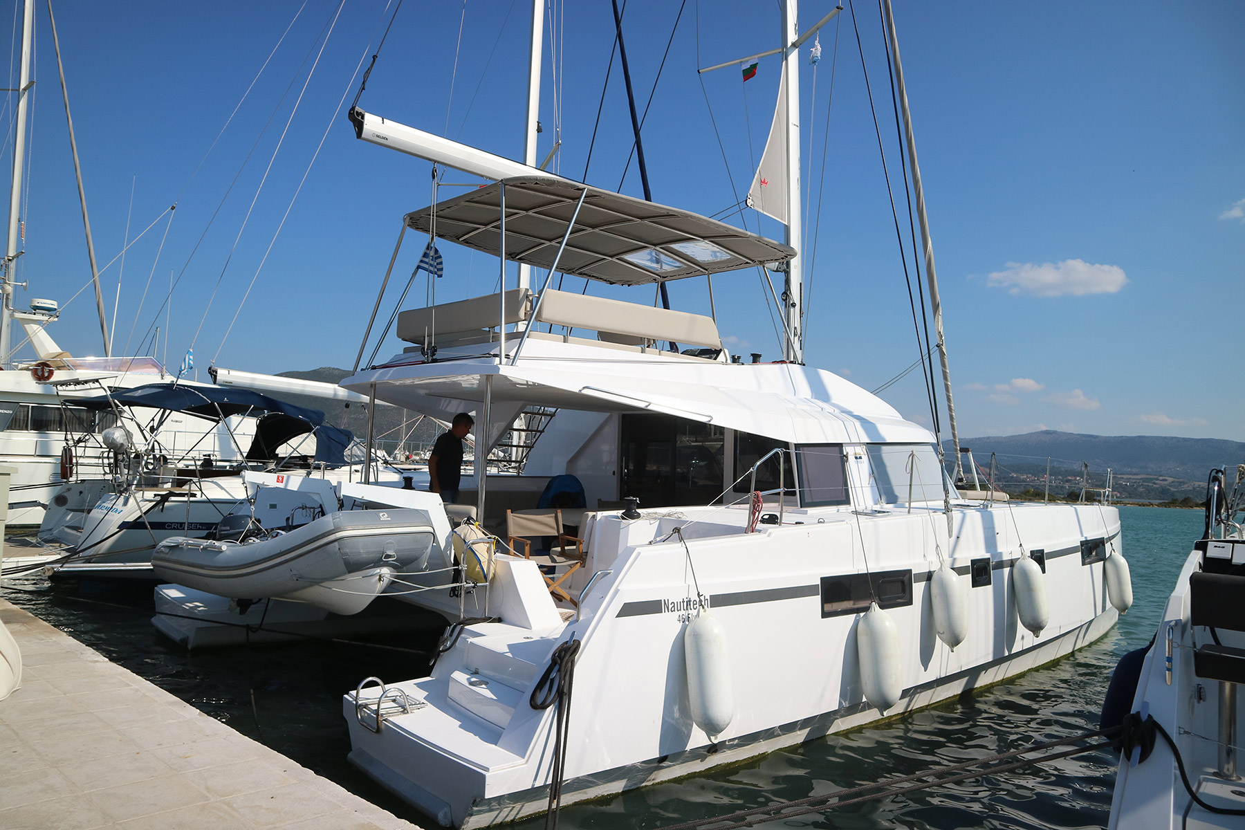 Private catamaran approaching Milos volcanic coastline from Crete