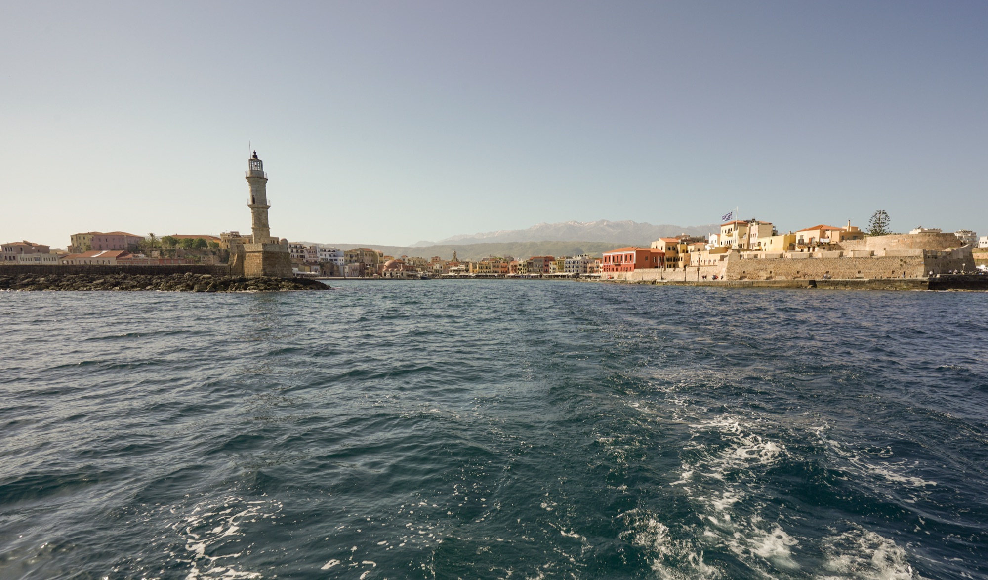 Chania's Venetian harbour and lighthouse seen from the sea with the White Mountains behind