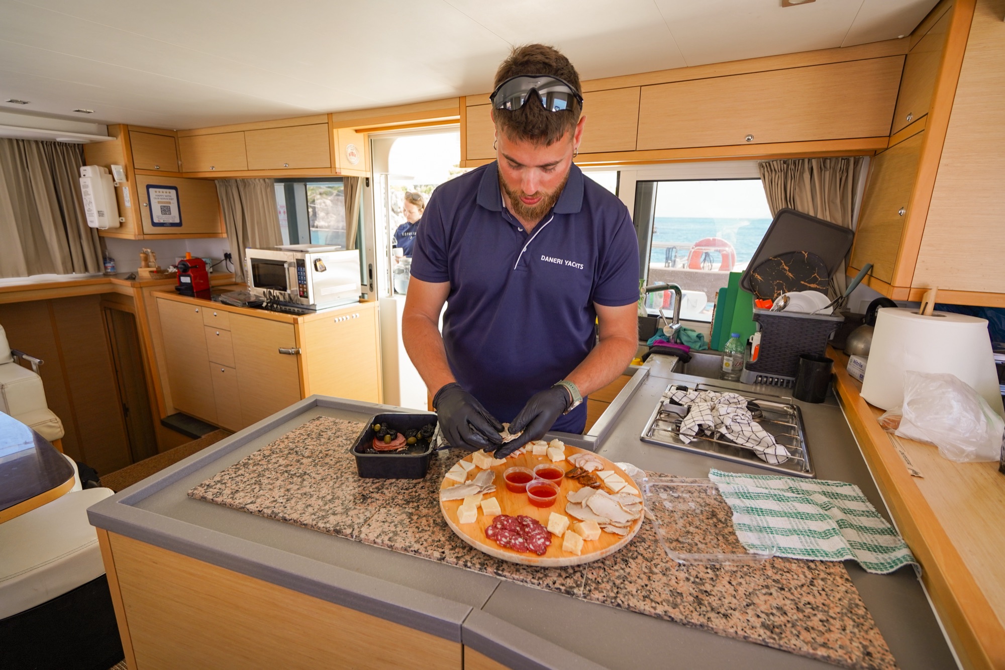 A DanEri crew member plating a Cretan cheese and meze platter in the catamaran galley off Chania