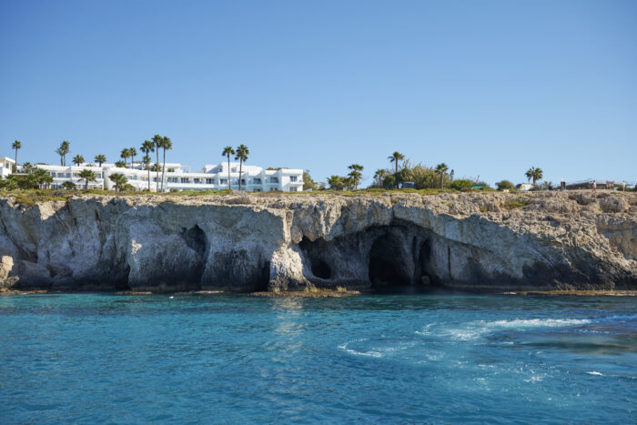 A DanEri catamaran sailing past the white cliffs of Cavo Greco in Cyprus